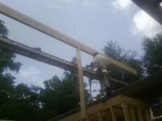 Carpenter setting a ridge beam over a new addition frame — Ice Dam Removal by Roofing Brothers in Nalcrest