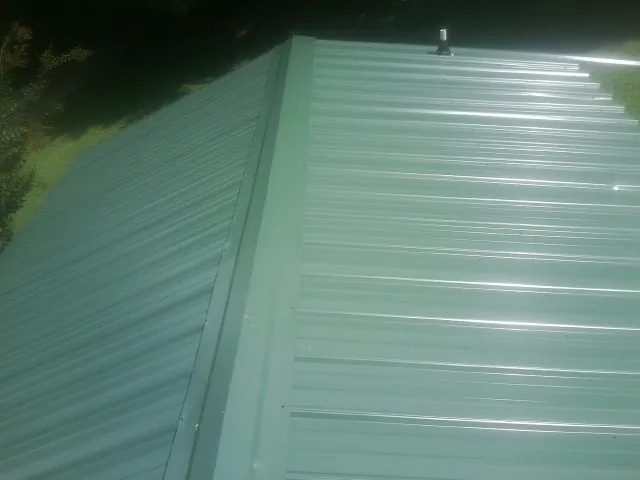 New green metal panels meeting at the ridge of a roof — Flat Roof Repair work by our crew in Nalcrest