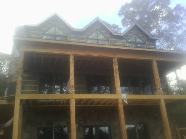 Dormers and porch framing on a large log home under construction — Roof Coating work by our crew in Nalcrest