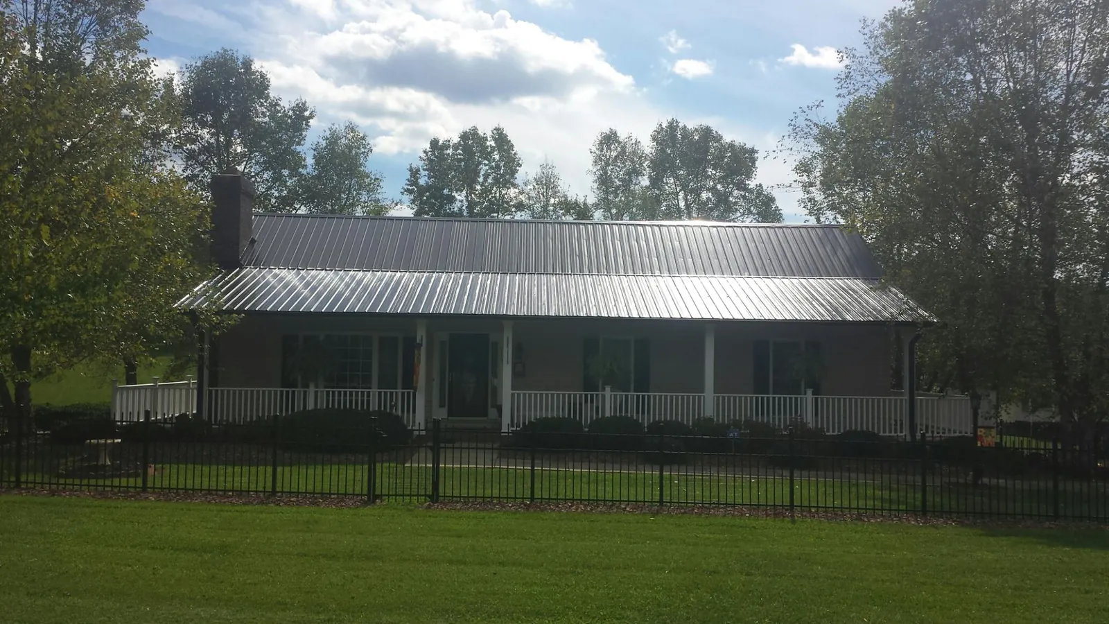 Gray metal roof on a brick ranch with a full width front porch — Gutter Guard Installation work by our crew in Nalcrest