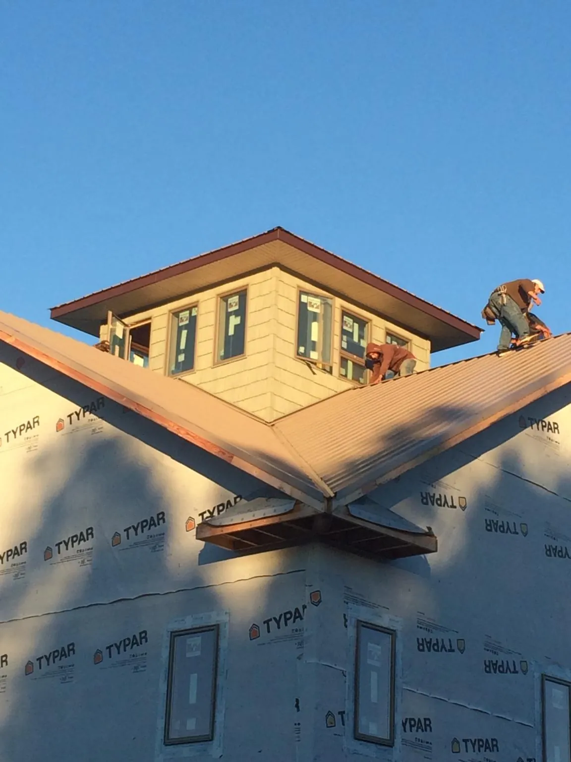 Roofers working around a rooftop cupola on a new metal roof at sunset — Roof Waterproofing in Nalcrest by Roofing Brothers